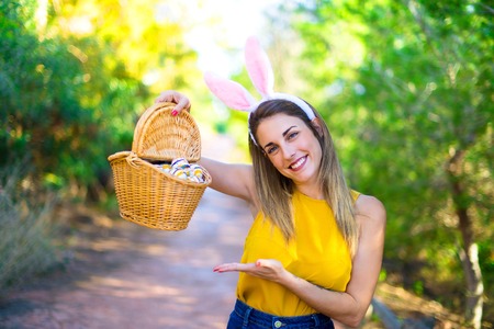 Young woman wearing bunny ears and with colorful Easter egg at outdoors