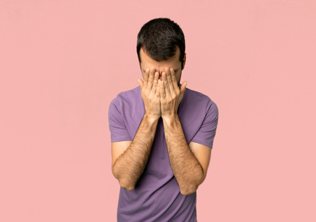 Handsome man with tired and sick expression on isolated pink backgroundの写真素材