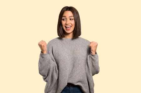 Young woman celebrating a victory on isolated yellow backgroundの写真素材