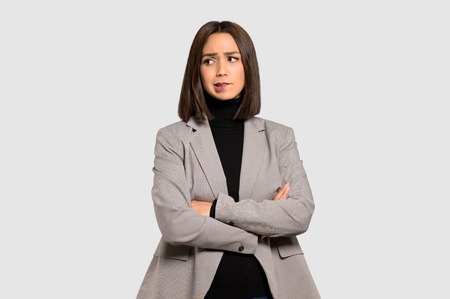 Young business woman with confuse face expression while bites lip on isolated grey backgroundの写真素材