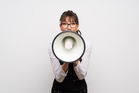 Young woman with apron shouting through a megaphoneの写真素材