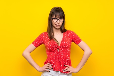 Young woman over yellow wall angry