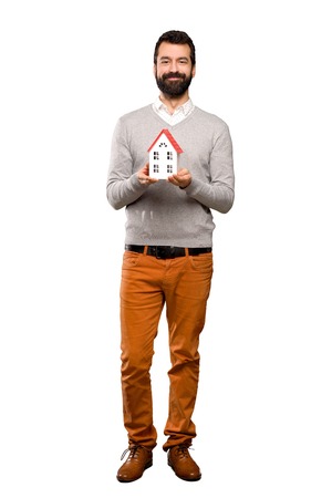 Handsome man with beard holding a little house over isolated white backgroundの写真素材