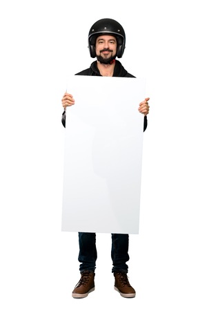 Full-length shot of Biker man holding an empty placard over isolated white backgroundの写真素材