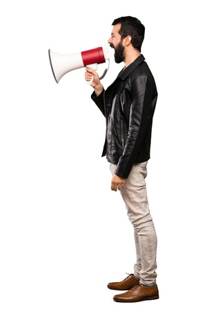 Handsome man with beard shouting through a megaphone over isolated white backgroundの写真素材