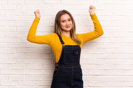Teenager girl over white brick wall proud and self-satisfiedの写真素材