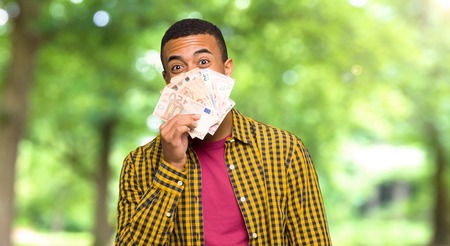 Young afro american man taking a lot of money in a parkの写真素材