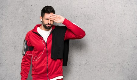 Handsome sportman with tired and sick expression over textured wallの写真素材