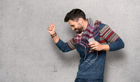 Hippie man listening music with the phone over textured wallの写真素材
