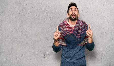 Hippie man surprised and pointing up over textured wallの写真素材