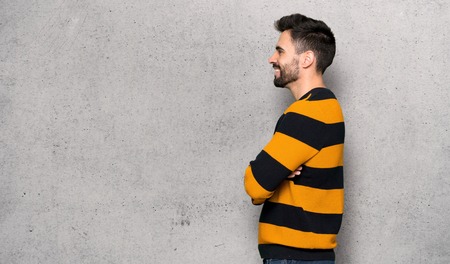 Handsome man with striped sweater in lateral position over textured wallの写真素材