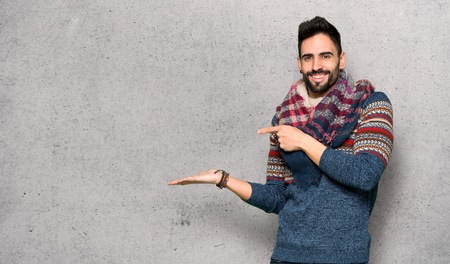 Hippie man holding copyspace imaginary on the palm to insert an ad over textured wallの写真素材