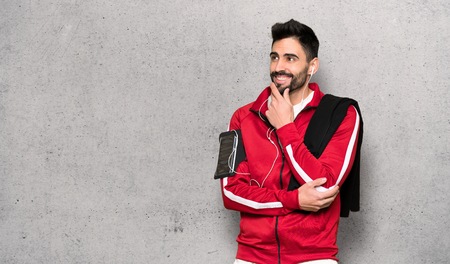 Handsome sportman thinking an idea while looking up over textured wall