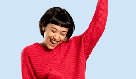 Short hair girl with red sweater celebrating a victory on isolated blue backgroundの写真素材