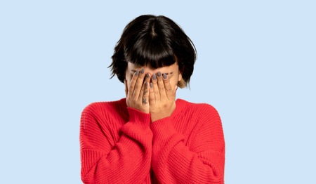Short hair girl with red sweater with tired and sick expression on isolated blue background
