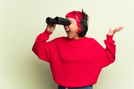 Young woman with red sweater and looking in the distance with binocularsの写真素材