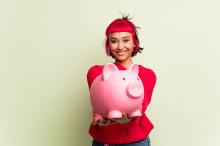 Young woman with red sweater holding a piggybankの写真素材