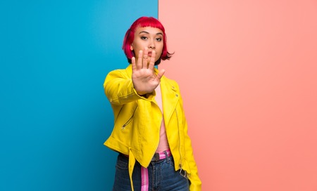 Young woman with yellow jacket making stop gesture denying a situation that thinks wrongの写真素材