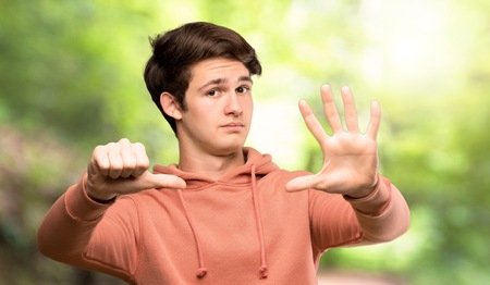 Teenager man with sweatshirt counting six with fingers at outdoorsの写真素材