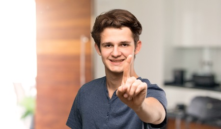 Teenager man showing and lifting a finger at indoorsの写真素材