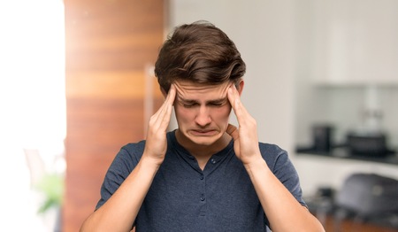 Teenager man with headache at indoorsの写真素材