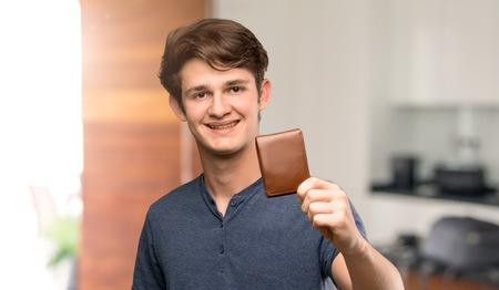 Teenager man holding a wallet at indoorsの写真素材