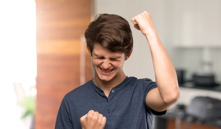 Teenager man celebrating a victory at indoorsの写真素材