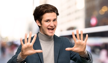 Teenager man with turtleneck counting ten with fingers at outdoorsの写真素材