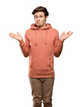 Teenager man with sweatshirt having doubts while raising hands over isolated white backgroundの写真素材