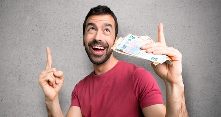 Man taking a lot of money pointing with the index finger a great idea over textured wall