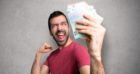 Man taking a lot of money celebrating a victory over textured wallの写真素材