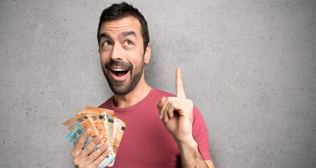 Man taking a lot of money thinking an idea pointing the finger up over textured wallの写真素材