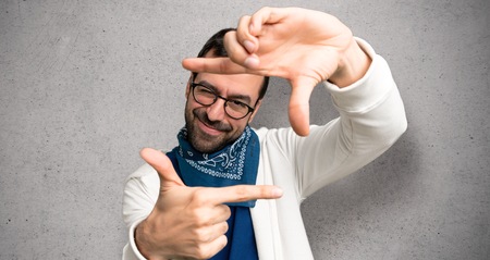 Handsome man with glasses focusing face. Framing symbol over textured wallの写真素材