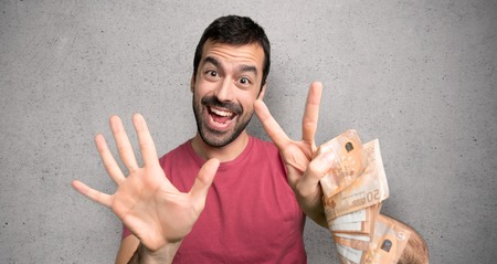 Man taking a lot of money counting seven with fingers over textured wallの写真素材