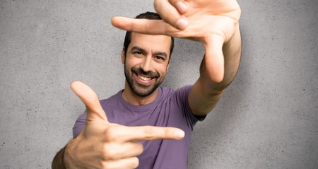 Handsome man focusing face. Framing symbol over textured wallの写真素材