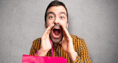 Man with shopping bags shouting and announcing something over textured wallの写真素材