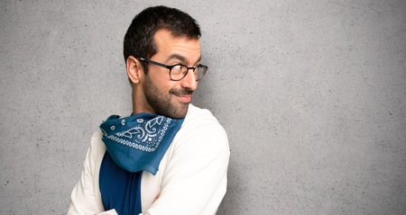 Handsome man with glasses looking over the shoulder with a smile over textured wallの写真素材