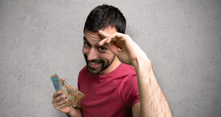 Man taking a lot of money saluting with hand over textured wall