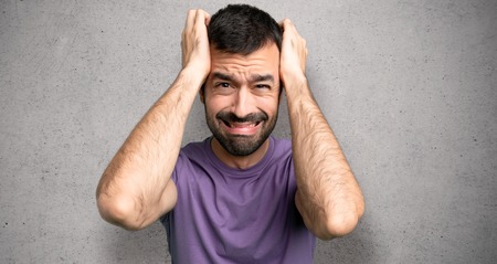 Handsome man takes hands on head because has migraine over textured wall