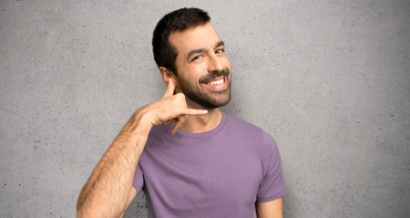 Handsome man making phone gesture. Call me back sign over textured wall