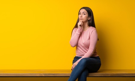 Young woman sitting on table thinkingの写真素材