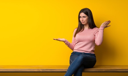 Young woman sitting on table unhappy because not understand somethingの写真素材