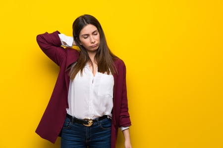Young woman over yellow wall with neckacheの写真素材