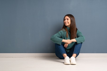 Young woman sitting on the floor smilingの写真素材