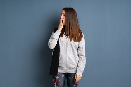 Young sport woman yawning and covering wide open mouth with handの写真素材