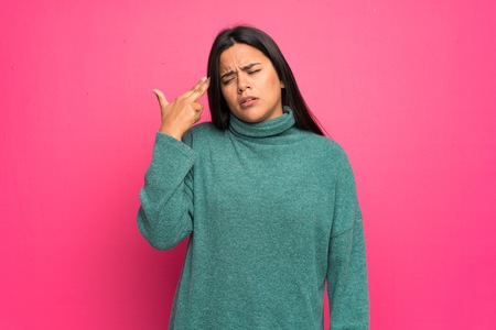 Young Colombian girl with green sweater with problems making gun gestureの写真素材