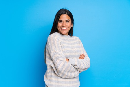 Young Colombian girl with sweater keeping the arms crossed in lateral position while smilingの写真素材