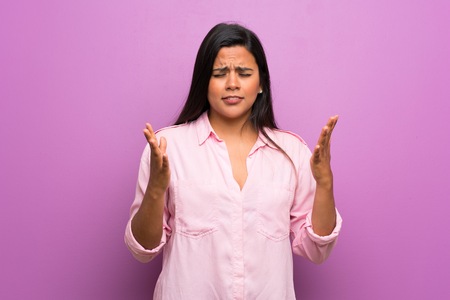 Young Colombian girl over purple wall frustrated by a bad situationの写真素材