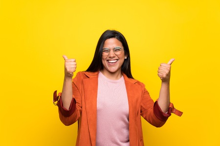 Young Colombian girl over yellow wall celebrating a victory in winner positionの写真素材