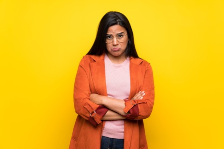 Young Colombian girl over yellow wall with sad and depressed expressionの写真素材